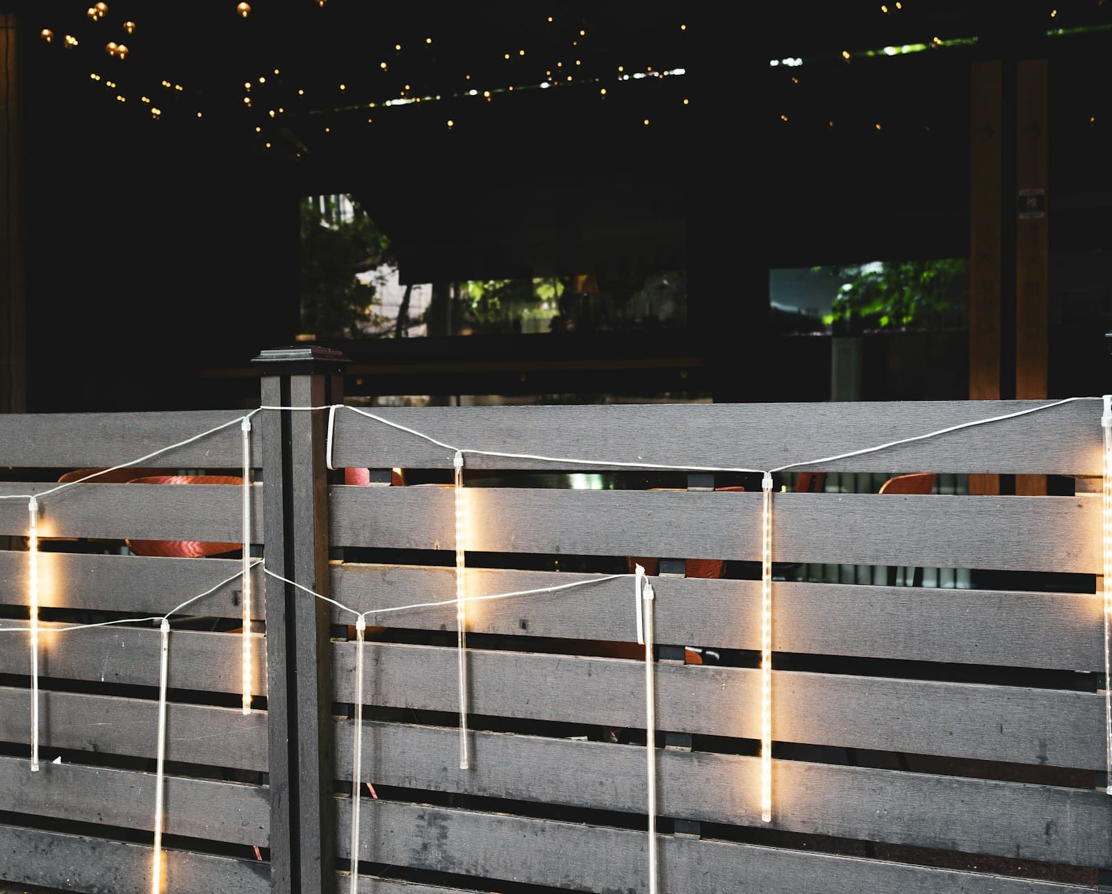 Fiesta en una terraza con guirnaldas de luces y gente charlando al anochecer