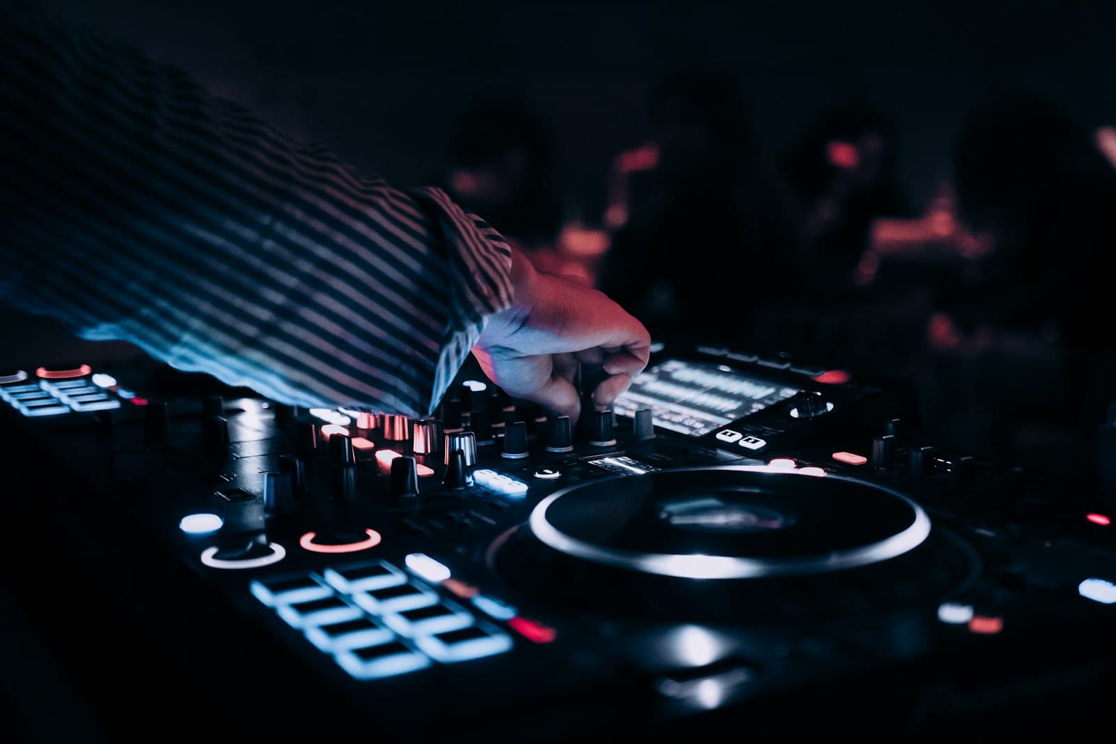 Manos de un DJ manejando los platos y el mezclador de una Pioneer XDJ durante una fiesta