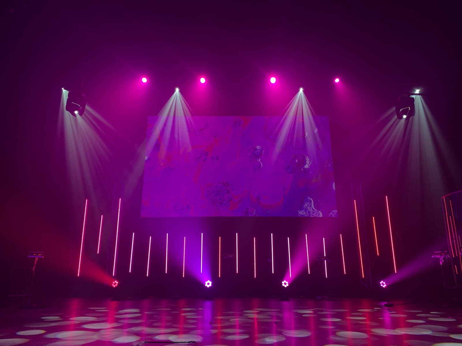 Focos LED de colores colocados en el suelo iluminando la pared de una sala de eventos