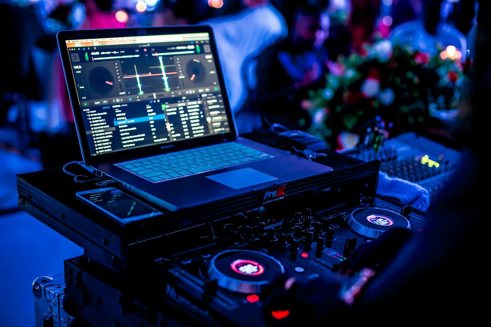 Controladora de DJ junto a un ordenador portátil abierto en una cabina iluminada